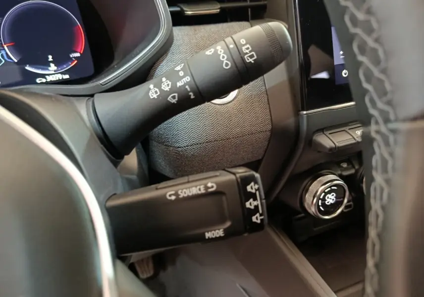Gros plan sur les commandes de volant et tableau de bord numérique de la Renault Clio Techno TCe 90 rouge 2024.