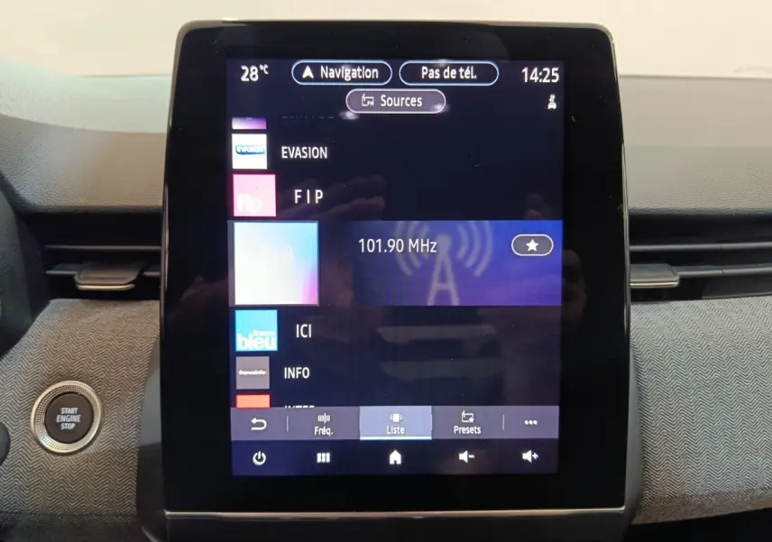 Écran tactile central de la Renault Clio Techno TCe 90 2024 affichant la radio FM et bouton démarrage à gauche.