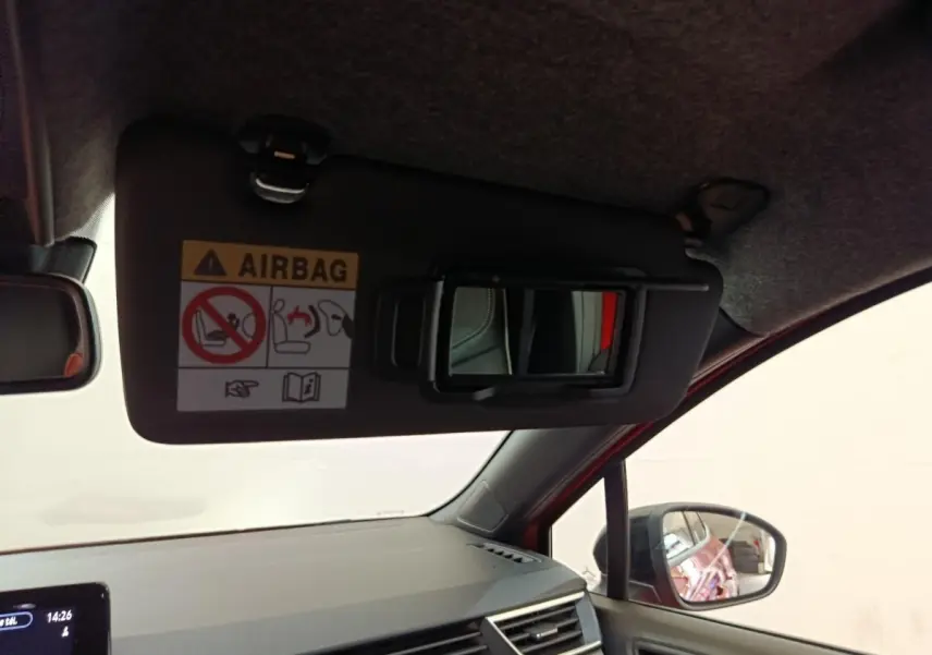 Intérieur de la Renault Clio Techno TCe 90 2024 rouge, vue côté passager avec pare-soleil et miroir ouvert.