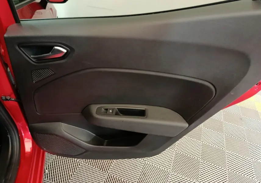 Vue intérieure de la porte avant gauche rouge de la Renault Clio 2024 avec poignée et commande de vitre.