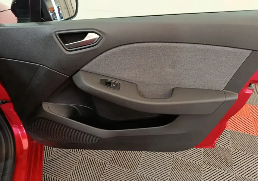 Vue rapprochée de la porte avant gauche rouge de la Renault Clio 2024 avec garniture noire et grise.