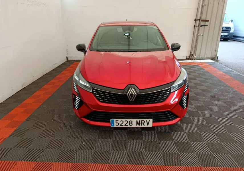 Vue frontale d'une Renault Clio rouge 2024 avec calandre noire et phares LED distinctifs dans un garage.
