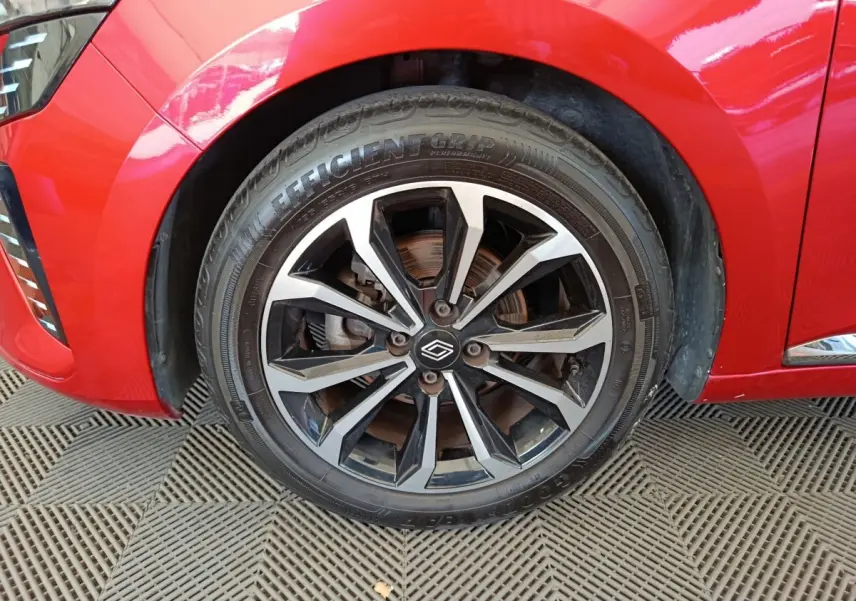 Gros plan sur la roue avant gauche de la Renault Clio rouge 2024, mettant en valeur la jante alliage noire et argent.