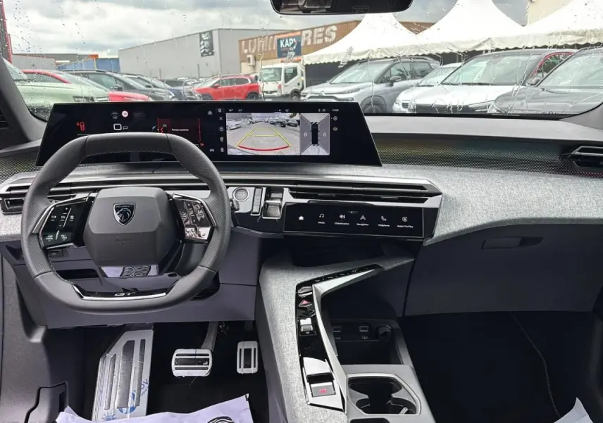 Vue intérieure du Peugeot 3008 Hybrid 2026 côté conducteur, avec tableau de bord numérique panoramique et volant compact noir.