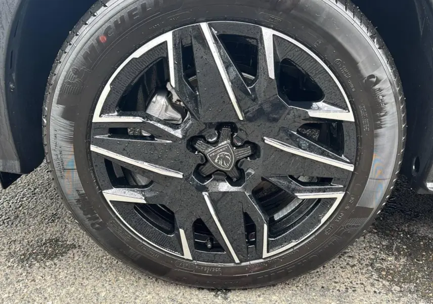 Gros plan sur la jante alliage 19'' diamantée noire et argentée du Peugeot 3008 noir Perla, roue mouillée.