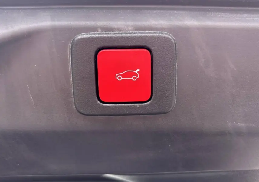 Bouton rouge d'ouverture électrique du hayon sur le coffre d'un Peugeot 3008 noir Perla.