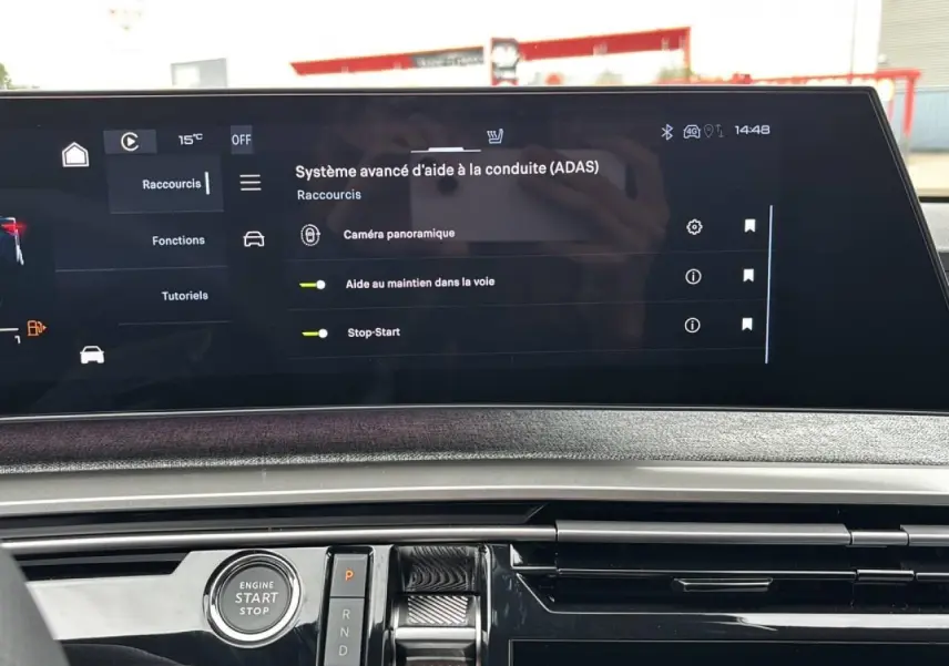 Vue intérieure du tableau de bord du Peugeot 3008 Hybrid 2026, écran tactile affichant l'aide à la conduite, bouton démarrage visible.