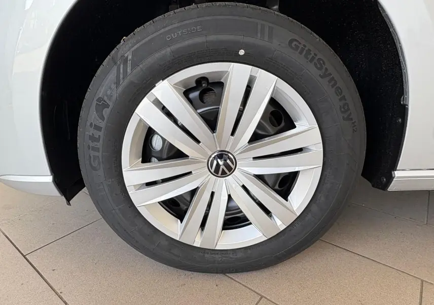 Gros plan sur la roue avant gauche gris argent du Volkswagen Caddy 2025 avec jante en alliage et logo VW central.