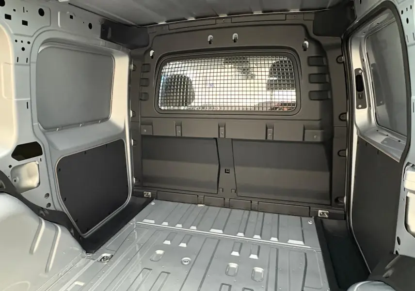 Vue intérieure de la zone de chargement du Volkswagen Caddy 2025 gris argent avec cloison métallique séparant l'habitacle.