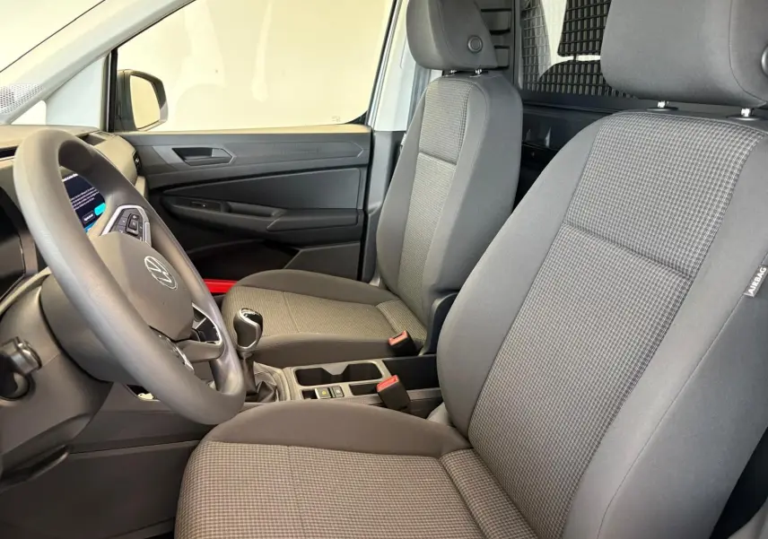 Intérieur du Volkswagen Caddy 2025 en gris argent, vue côté conducteur montrant sièges et volant avec levier de vitesse manuel.