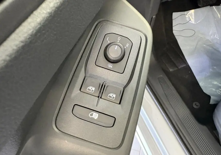 Gros plan sur les commandes des rétroviseurs et vitres côté conducteur du Volkswagen Caddy gris argent 2025.