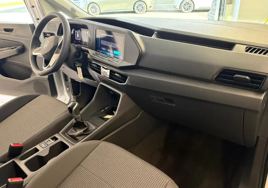 Intérieur du Volkswagen Caddy 2025 gris argent, vue côté conducteur sur le tableau de bord et la boîte manuelle.