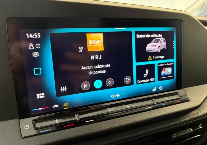 Écran tactile central du Volkswagen Caddy 2025 gris argent, affichant radio NRJ et statut véhicule avec message d'alerte.