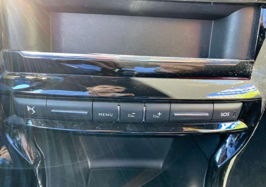 Boutons de commande du système audio et SOS sur la console centrale brillante d'une DS3 rouge toit blanc vue de face.