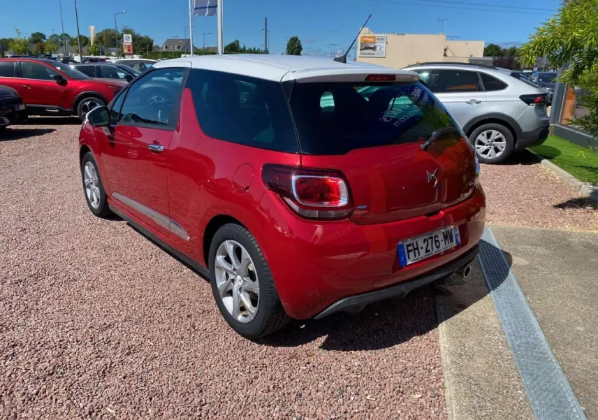 Vue 3/4 arrière droite d'une DS3 rouge à toit blanc, avec jantes alliage et plaque d'immatriculation française.