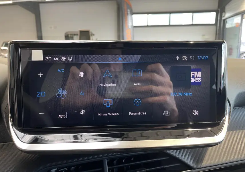 Écran tactile central du Peugeot 208 2025 affichant la climatisation et les options multimédia, avec cadre noir brillant.