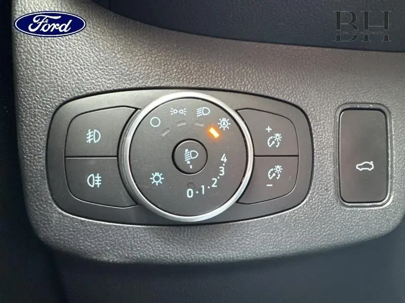 Gros plan sur les commandes d’éclairage et hayon électrique du Ford Puma blanc, intérieur noir.