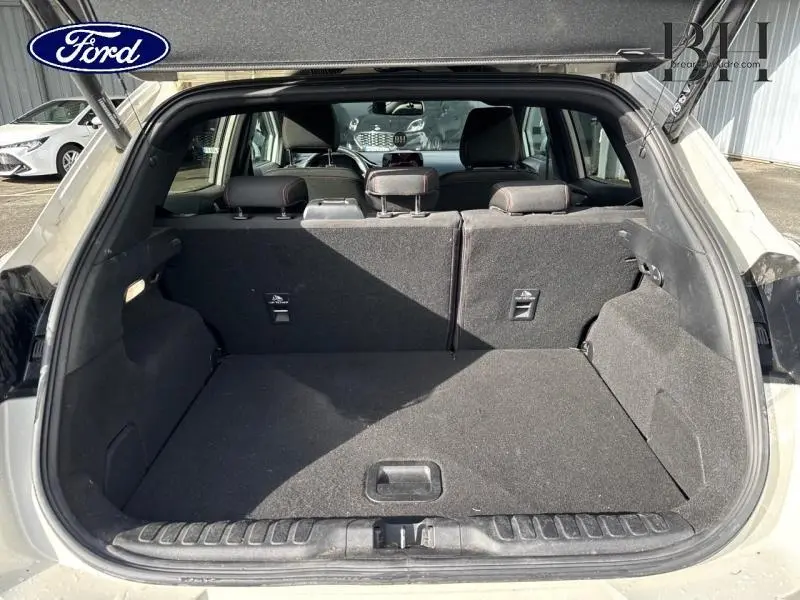 Vue arrière du coffre ouvert d’un Ford Puma blanc Premium Metropolis, montrant l’espace de chargement et la banquette arrière.