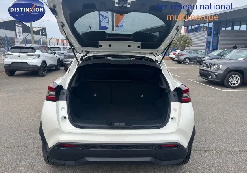 Vue arrière d’un Nissan Juke blanc nacré 2024 avec coffre ouvert, montrant l’espace de chargement vide.