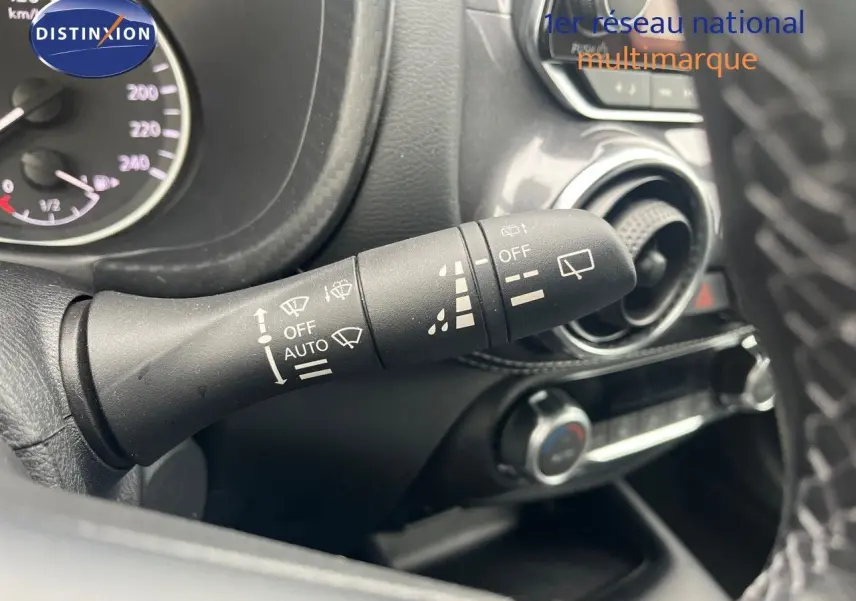 Gros plan sur la commande d’essuie-glace à gauche du volant dans l’habitacle du Nissan Juke blanc nacré 2024.