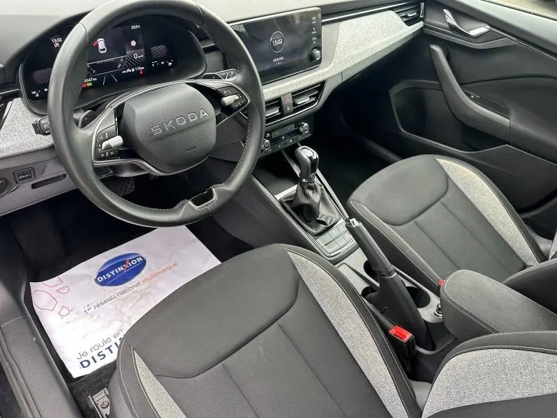 Vue intérieure côté conducteur de la Skoda Scala 2025, volant cuir multifonction et sièges tissu noir et gris.