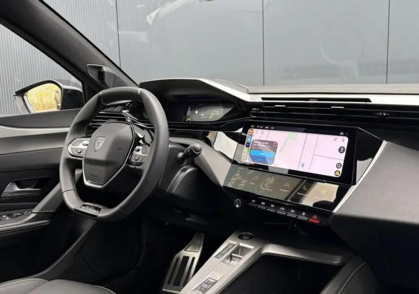 Vue intérieure côté conducteur du Peugeot 308 SW gris, volant compact GT, écran tactile et combiné numérique 3D.