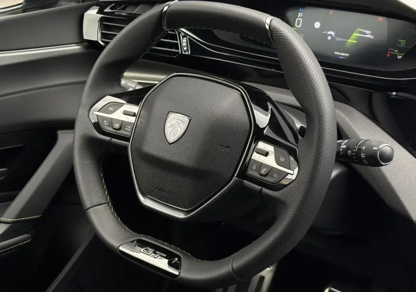 Vue rapprochée du volant GT en cuir noir avec surpiqûres vertes et combiné numérique du Peugeot 308 SW 2026.