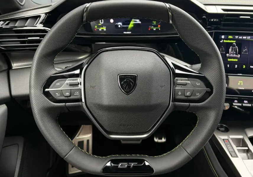 Vue rapprochée du volant GT en cuir noir avec surpiqûres vert Adamite du Peugeot 308 SW Hybrid 2026.
