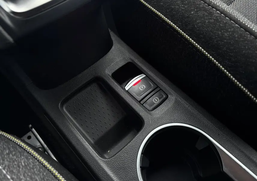 Gros plan sur la console centrale noire du Renault Captur 2025, avec bouton frein électrique et accoudoir tissu.