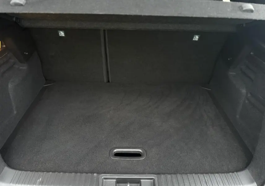 Vue intérieure du coffre spacieux et plat du Renault Captur TCE 100 Techno 2025, revêtement noir uniforme.