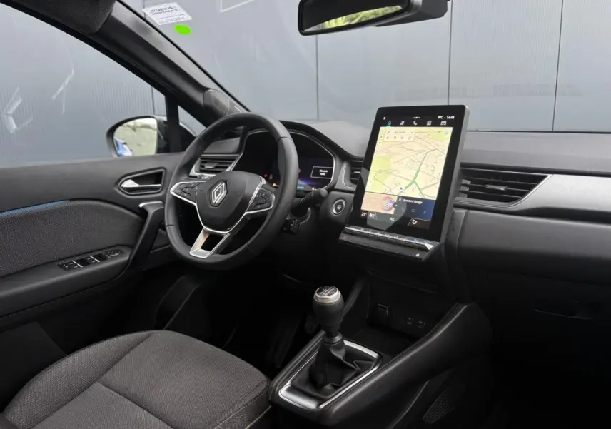 Vue intérieure côté conducteur du Renault Captur TCE 100 Techno 2025, avec tableau de bord numérique et écran tactile vertical.