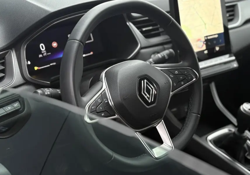 Vue intérieure rapprochée du volant noir du Renault Captur 2025 avec tableau de bord numérique et écran tactile GPS.