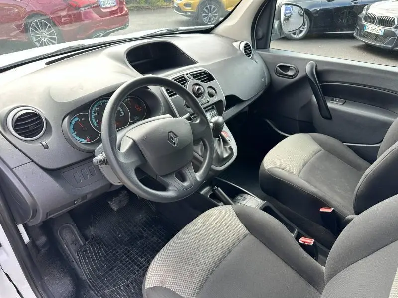 Vue intérieure côté conducteur du Renault Kangoo Express électrique blanc minéral, volant et tableau de bord visibles.