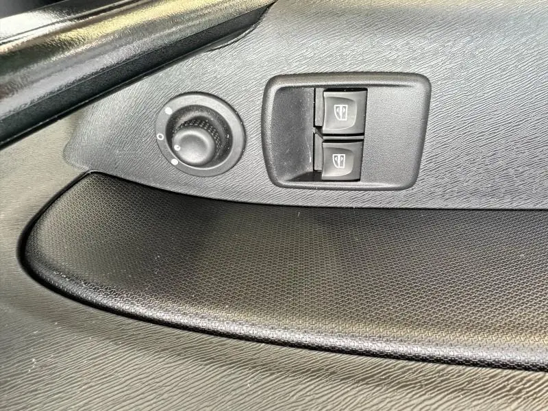 Gros plan sur les commandes des vitres électriques et réglage des rétroviseurs côté conducteur du Renault Kangoo Express blanc minéral 2022.