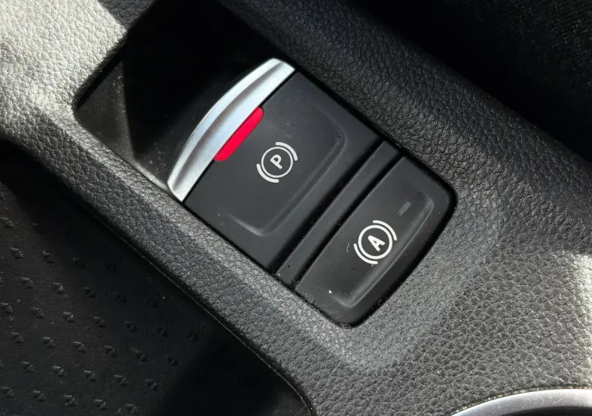 Gros plan sur les boutons du frein de parking électrique et de l'arrêt automatique dans l'habitacle du Renault Captur E-Tech rouge.