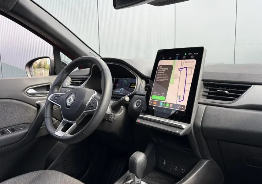 Vue intérieure côté conducteur du Renault Captur E-Tech 2025, avec écran tactile vertical et volant multifonctions noir.