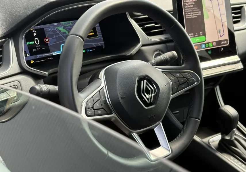 Vue rapprochée du volant cuir multifonctions et tableau de bord numérique du Renault Captur E-Tech 2025.