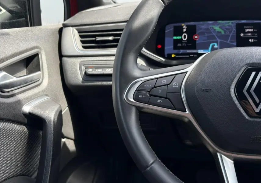 Gros plan sur le volant cuir multifonctions et le tableau de bord numérique du Renault Captur E-Tech 2025.