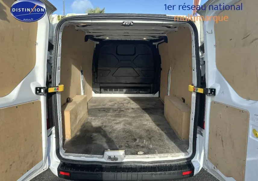Vue arrière du fourgon blanc Ford Transit Custom avec portes ouvertes montrant l’espace de chargement vide et protégé.