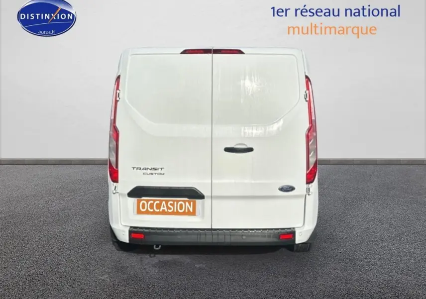 Vue arrière d'un Ford Transit Custom blanc avec portes battantes et plaque "OCCASION" visible.