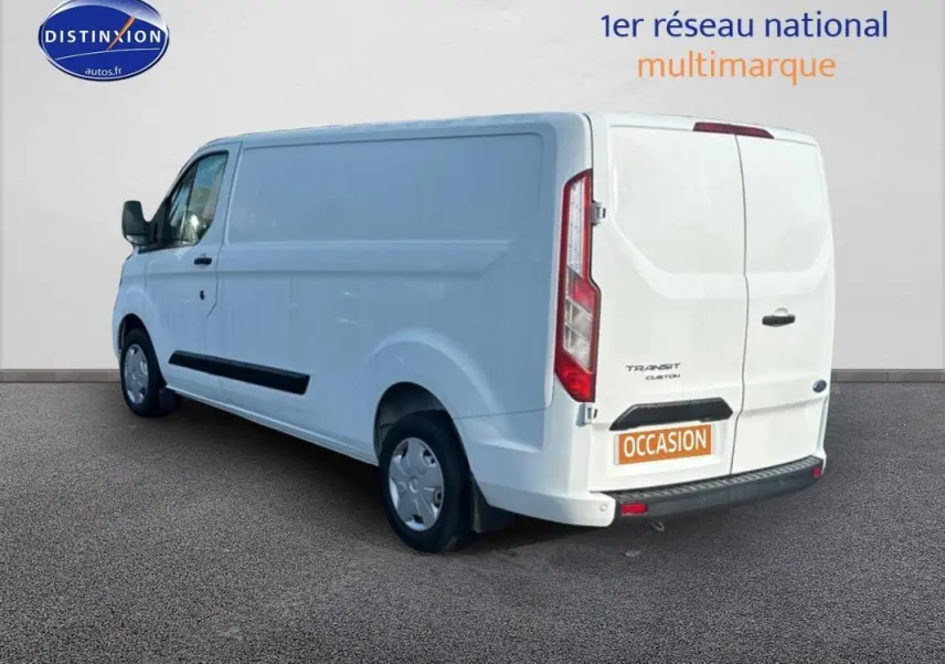 Vue 3/4 arrière droite d’un Ford Transit Custom blanc, fourgon utilitaire avec porte latérale et vitres surteintées.