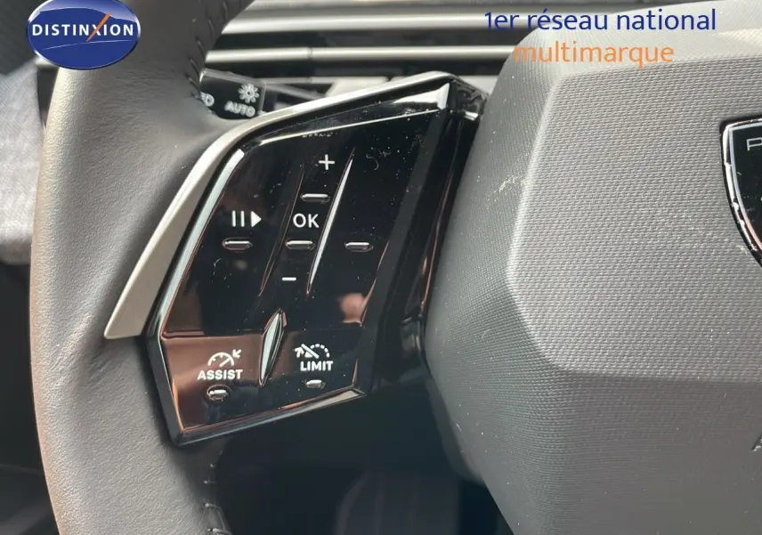 Gros plan sur les commandes à gauche du volant du Peugeot 3008 Hybrid gris Artense, avec boutons d'assistance et limitation.