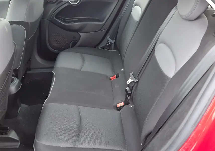 Vue intérieure avant de la Fiat 500X rouge de 2016, avec volant multifonction, tableau de bord rouge brillant et boîte manuelle.