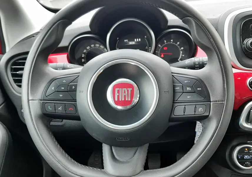Vue plongeante sur la console centrale noire du Fiat 500X rouge, avec porte-gobelets et leviers de frein à main visibles.