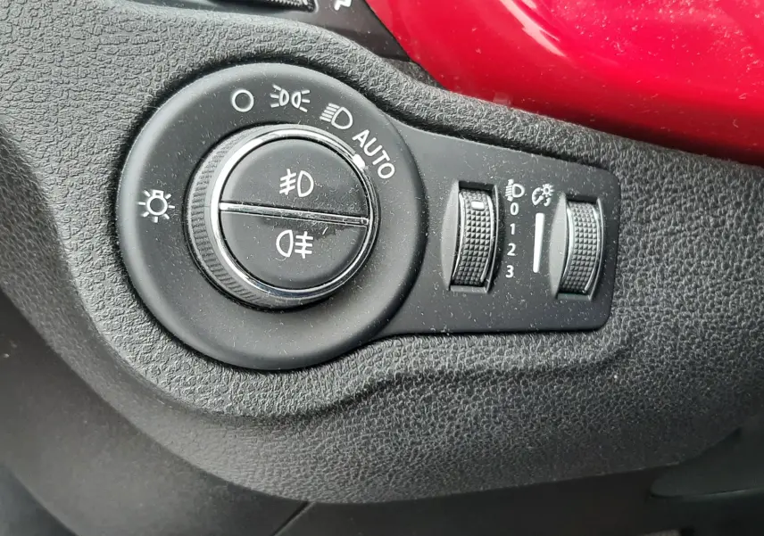 Gros plan sur les commandes au volant côté gauche du FIAT 500X rouge, avec boutons de navigation et appels intégrés.