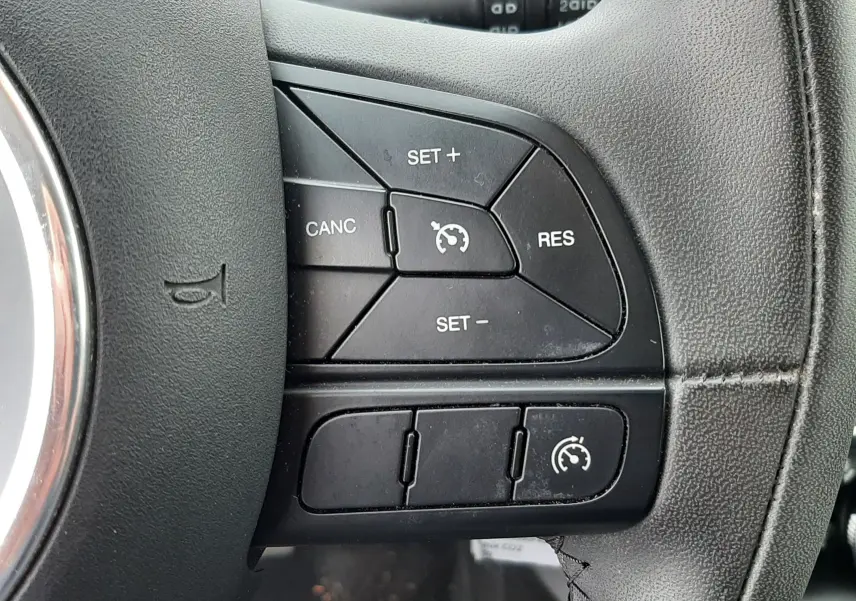 Gros plan sur le bouton de frein à main électrique allumé dans la console centrale d'une Fiat 500X rouge de 2016.