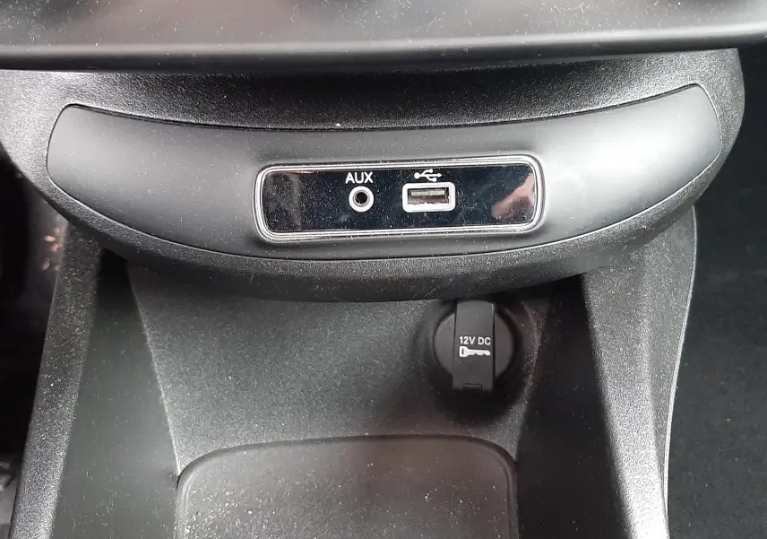 Gros plan sur les commandes de climatisation automatique et les prises AUX et USB du tableau de bord d'une Fiat 500X rouge.