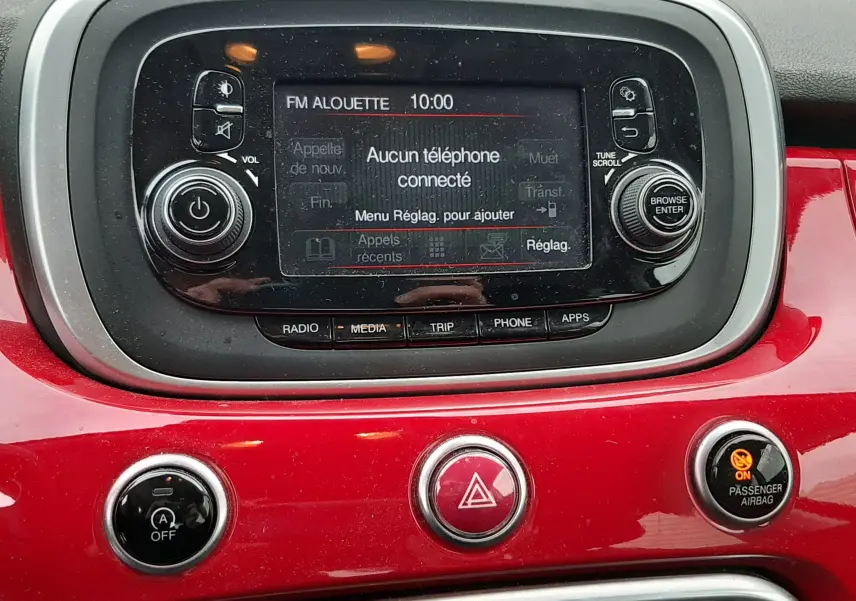 Gros plan sur l'écran multimédia central de la Fiat 500X rouge, affichant la radio FM sur la station Alouette 98.30 MHz.