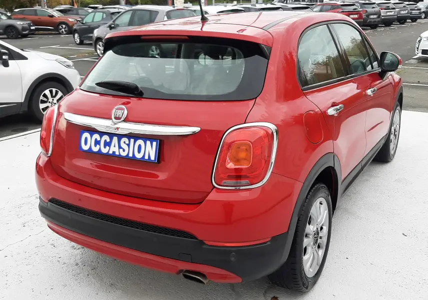 Vue arrière d'une FIAT 500X rouge avec plaque "OCCASION" sur un parking extérieur.