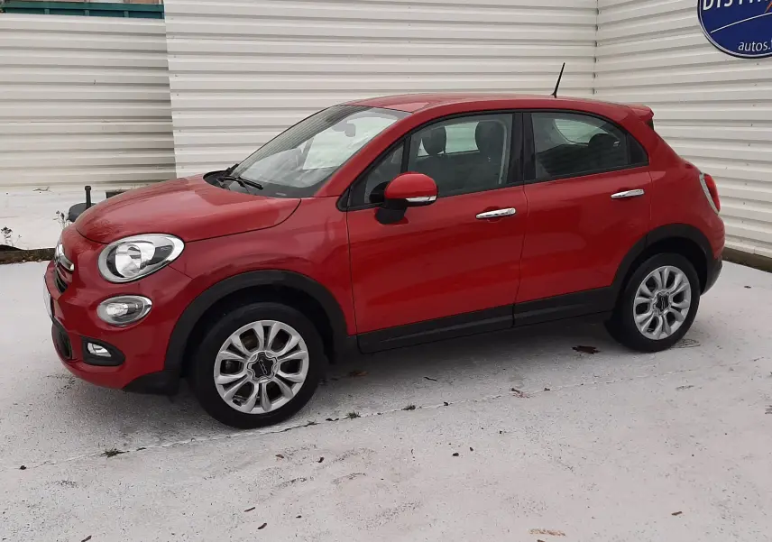 Vue 3/4 avant droit d'une FIAT 500X rouge avec rétroviseur et poignées chromées sur fond clair.